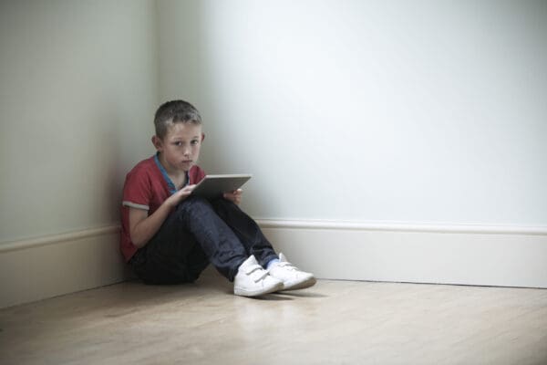 Unhappy,Child,Sitting,In,Room,With,Digital,Tablet